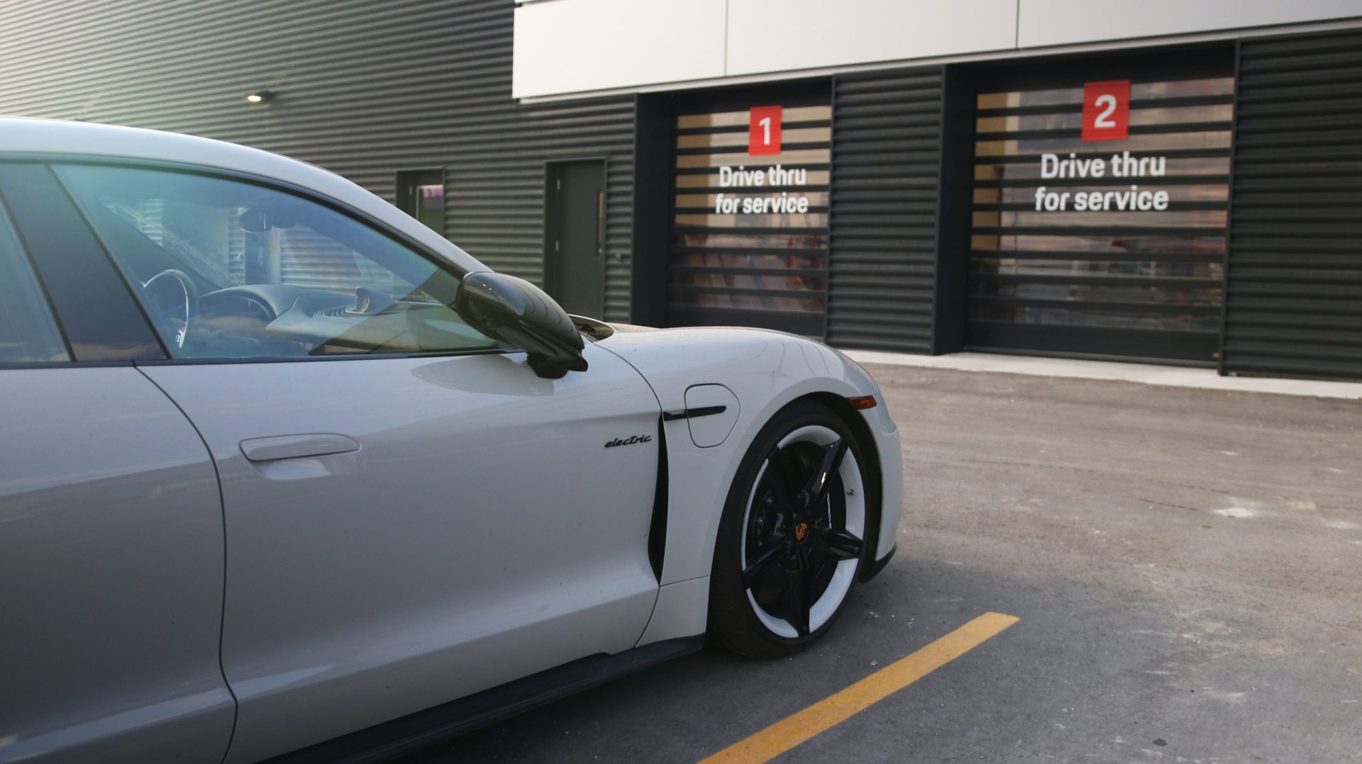 Porsche electric vehicle parked in front of drive-thru service area, featuring signage for service access at Porsche Centre Markham.