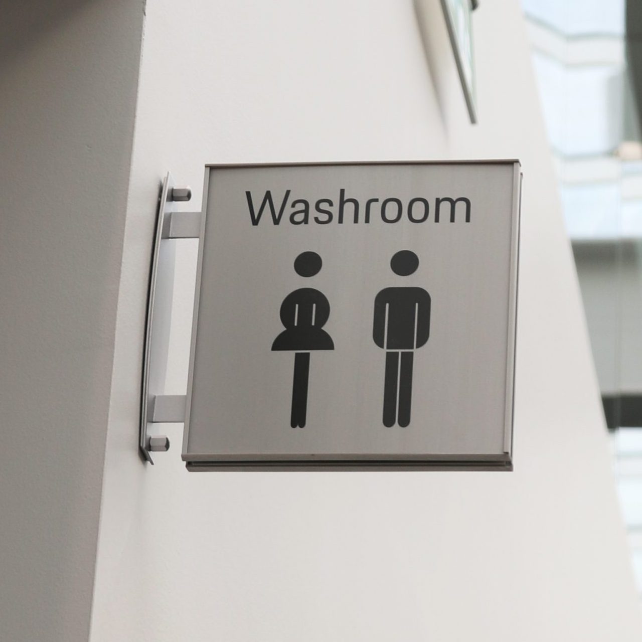 Washroom signage featuring male and female symbols, indicating restroom facilities, part of compliance with Ontario Building Code for the Porsche Centre Markham project.